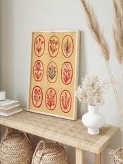 Botanical grid wall art print featuring nine red floral and leaf illustrations inside oval, in an alternate framed mockup