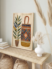 Illustrative wall art print of a tall potted plant next to a geometric patterned woven basket, in an alternate framed mockup