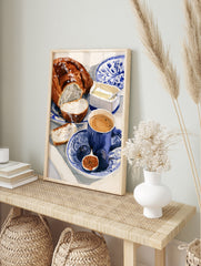 Watercolour illustration of a breakfast scene with bread, figs, and coffee on a blue and, in an alternate framed mockup
