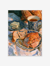Watercolour painting of a breakfast scene with bread, butter, and tea in a blue patterned mug on a draped cloth
