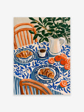 Still life breakfast illustration with croissants, coffee, oranges, and green leaves on a blue patterned tablecloth