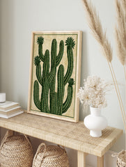 Stylised green cactus illustration with blooming flowers on a textured tan background, in an alternate framed mockup