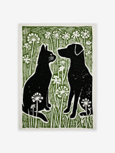Black cat and dog silhouettes facing each other in green grass with white flowers, linocut style print