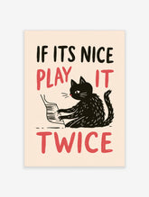 Illustrative wall art of a black cat playing the piano with red text reading IF ITS NICE PLAY IT TWICE on cream background
