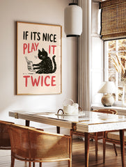 Illustrative wall art of a black cat playing the piano with red text reading IF ITS NICE PLAY IT, in a styled room mockup