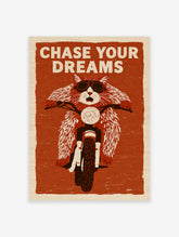 Illustration of a cat wearing goggles on a motorcycle with the text Chase Your Dreams on a textured red-orange background