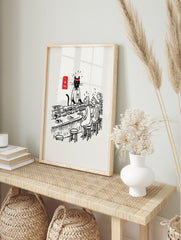 Illustrative print of a black cat sushi chef in uniform serving customers at a counter with, in an alternate framed mockup