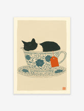 Whimsical cat wall art print featuring a black and white cat sleeping in a blue floral teacup with an orange tea tag.