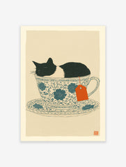 Whimsical cat wall art print featuring a black and white cat sleeping in a blue floral teacup with an orange tea tag.