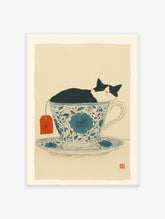 Black and white cat sleeping in a blue floral teacup with an orange tea tag, whimsical cat wall art print.