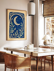 Illustrative deep blue botanical print with a cream crescent moon, stars, and leafy branches, in a styled room mockup