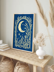 Illustrative cream crescent moon and stars with botanical foliage on a deep blue background, in an alternate framed mockup