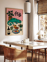 Illustrative green chameleon on a table with food, drinks, a plant, and Japanese characters on a, in a styled room mockup