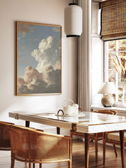 Dramatic cloud study painting with voluminous white and grey clouds against a soft blue sky, in a styled room mockup