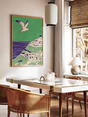 Illustrative coastal wall art print showing a white village on green hills, blue sea, and a flying seagull. - Image 2
