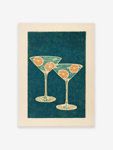 Illustrative cocktail wall art featuring two martini glasses with orange slices on a dark teal dotted background.