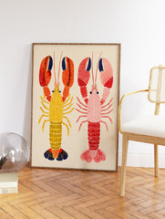 Two colorful illustrative lobster wall art prints, one yellow and orange, one pink and red, on a light beige background. - Image 2