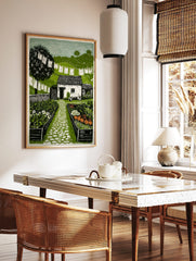 Linocut print of a cottage garden with a white building, cobbled path, raised beds, laundry, and, in a styled room mockup