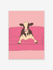 Illustrative art print of a black and white cow sitting on a pink couch against a pink background.