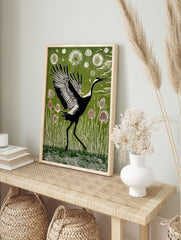 Black and white crane with widespread wings walking through green reeds and thistle plants in, in an alternate framed mockup