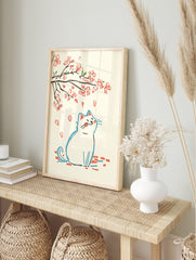 Illustrative print of a white cat looking up at falling pink cherry blossom petals and, in an alternate framed mockup