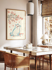 Illustrative print of a white cat looking up at falling pink cherry blossom petals and branches, in a styled room mockup