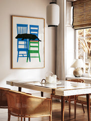 Black dachshund dog silhouette resting on stacked blue and green chairs, graphic illustration on, in a styled room mockup
