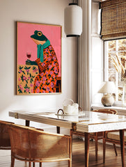 Whimsical painting of a frog in an orange floral robe, teal scarf, holding a wine glass against a, in a styled room mockup