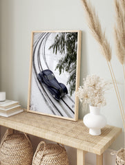 Dark blue vintage streamlined car on snow-covered railway tracks with fir branches in winter, in an alternate framed mockup