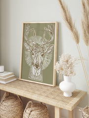 Illustrative deer head print with antlers and radial lines on a sage green background, in a, in an alternate framed mockup
