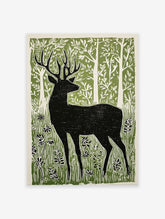 Black deer silhouette linocut print in a green forest with white trees and foliage, on a light background.