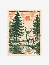 Vintage deer wall art featuring a stag in a green forest with pine trees and an orange sun in a woodcut illustration style.