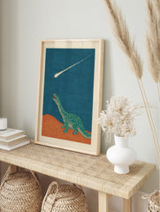 Illustrative green dinosaur looking up at a bright meteor streaking across a dark blue sky, in an alternate framed mockup