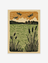 Linocut-style print of black dragonflies flying over a green pond with cattails and trees, under an orange sky