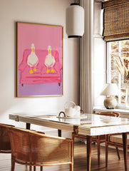 Two white ducks with yellow beaks and feet sitting on a pink couch, illustrated wall art print against a pink background. - Image 2