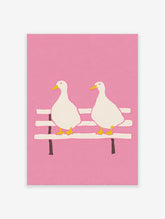 Illustrated pink duck wall art featuring two white ducks with yellow beaks and feet sitting on a bench against a pink background.