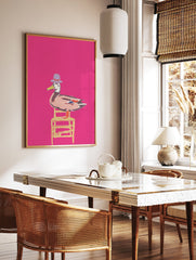 Whimsical duck wall art illustration wearing a purple hat and sitting on a yellow chair against a bright pink background. - Image 2