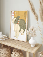 Illustrative print of a grey and white Dutch rabbit with a red ribbon and Japanese text on a, in an alternate framed mockup