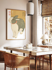 Illustrative print of a grey and white Dutch rabbit with a red ribbon and Japanese text on a beige, in a styled room mockup