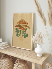 Illustrative botanical print of a cluster of orange-brown mushrooms with green leaves on a, in an alternate framed mockup