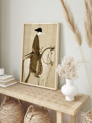 Illustrative print of a stylised figure in dark robe and black hat riding a white horse with, in an alternate framed mockup