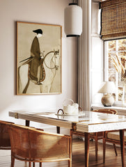 Illustrative print of a stylised figure in dark robe and black hat riding a white horse with, in a styled room mockup