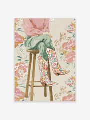 Illustrative print of a person's legs wearing colourful floral cowboy boots, sitting on a wooden stool against a floral