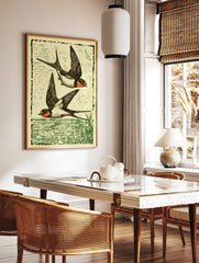 Illustrative print of two black and orange swallows flying over green water, with a woodcut style, in a styled room mockup