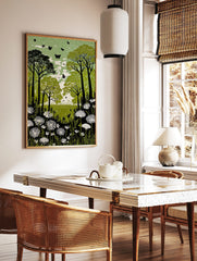 Green forest meadow print with dark trees, white flowers, and black butterflies in a linocut style, in a styled room mockup