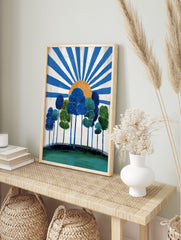 Stylised blue and green trees on a hill with an orange sun and radiating blue rays on a white, in an alternate framed mockup