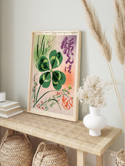 Four-leaf clover botanical illustration with Japanese calligraphy and red seal on pink and, in an alternate framed mockup