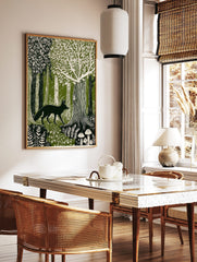 Linocut style forest art print with dark fox walking among green and white trees, ferns, and, in a styled room mockup