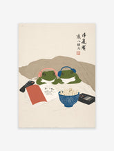 Humorous frog art print of two green frogs in headphones under a blanket, watching a movie with popcorn and a remote.