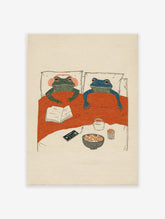 Whimsical frog wall art illustration of two frogs in bed with popcorn, a book, and headphones for a cozy night in.